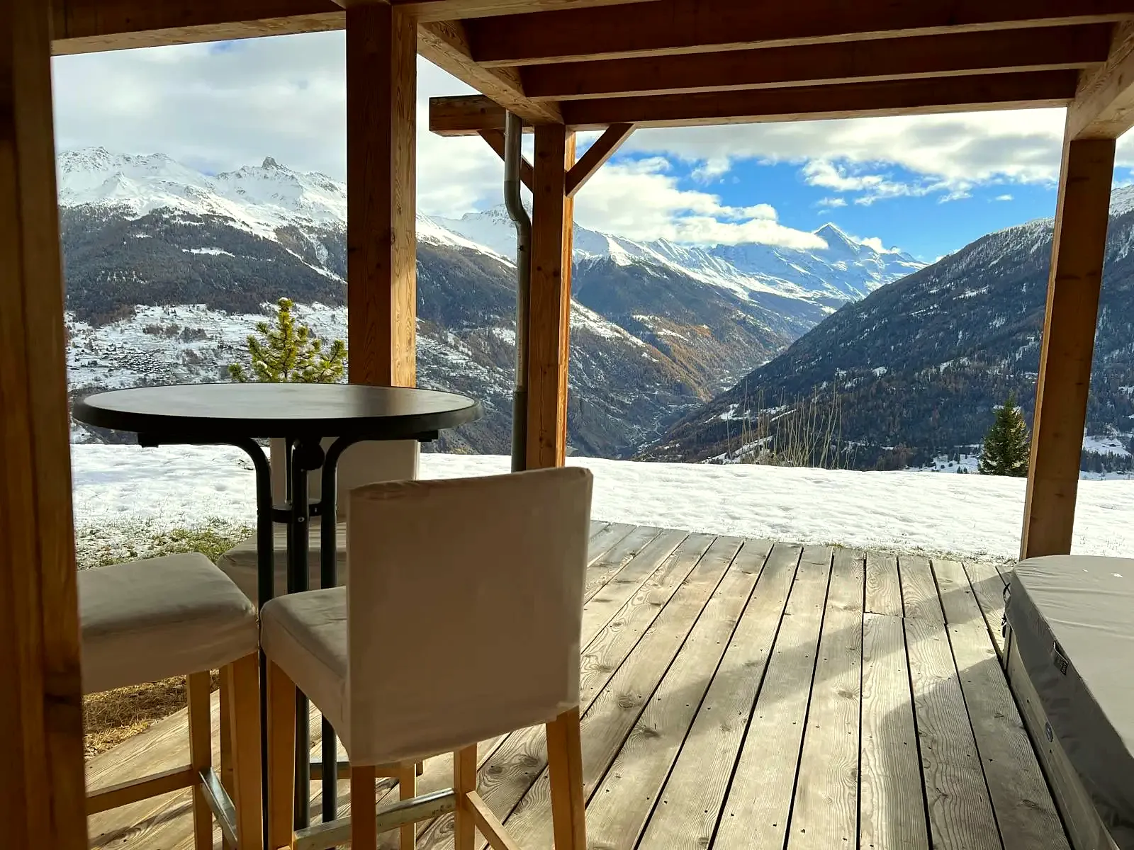 The covered terrace of the chalet in winter, a table and the snowy peaks